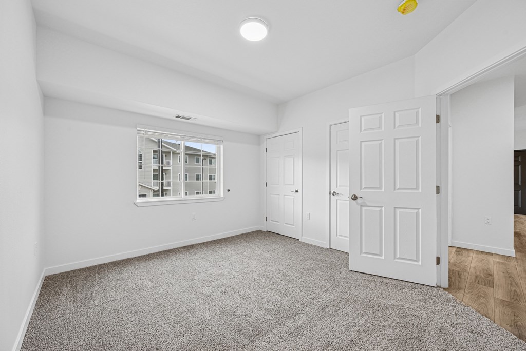 A spacious room with a carpeted floor and white walls.