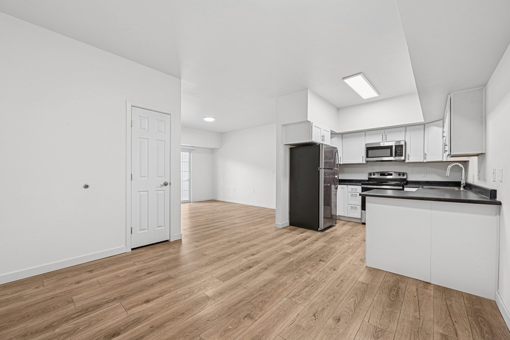 A kitchen with white cabinets and a black refrigerator.