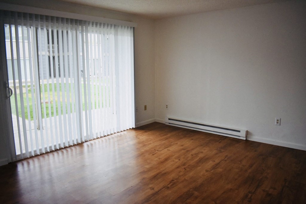 an empty living room with wood floors and white walls