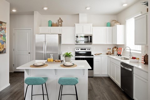 a kitchen with white cabinets and a white island with two stools