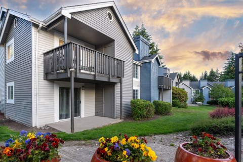 A building with a balcony and a flower pot in front.