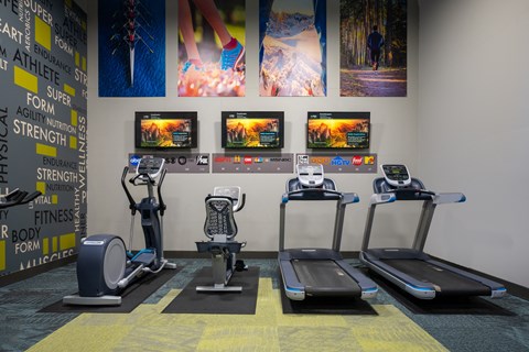 a row of exercise machines in a gym with pictures on the wall