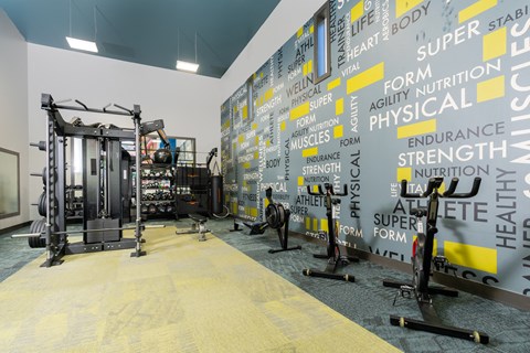 a gym with weights machines and a wall covered in logos