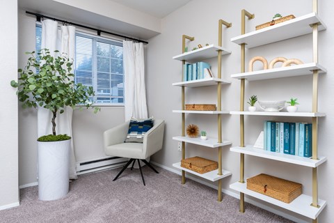 a room with a white chair and shelves and a window