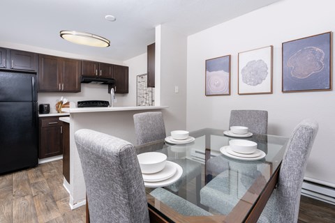 a dining area with a glass table and chairs and a kitchen
