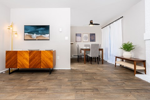 a living room and dining room with wood flooring and a cabinet and a table