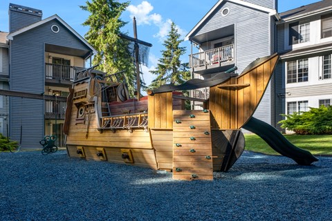 a large wooden ship playground in the middle of two houses