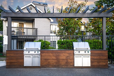 two gas barbecue grills in front of a house