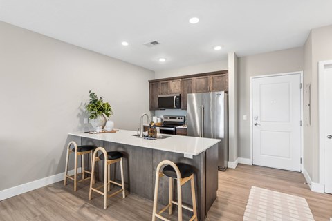 A kitchen with a white countertop and wooden bar stools.