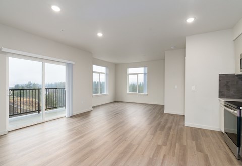 A spacious room with wooden flooring and a balcony with a black railing.