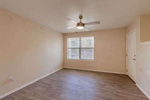 A room with a ceiling fan and a window with blinds.