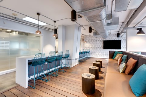 A modern office space with a long white table and blue chairs.