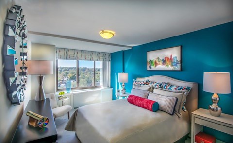 A bedroom with a large bed and a window overlooking a cityscape.