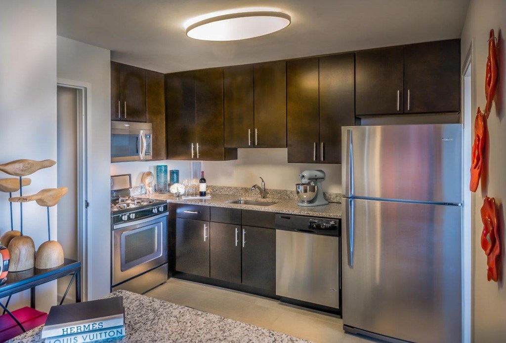 A modern kitchen with a refrigerator, oven, and sink.
