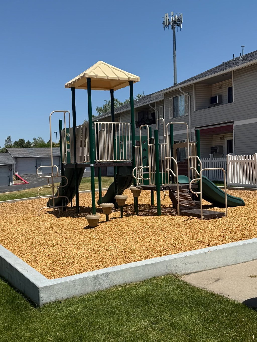 A playground with a yellow canopy and a green slide.