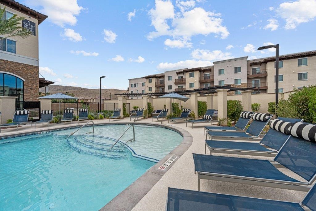 a swimming pool with lounge chairs and a building in the background