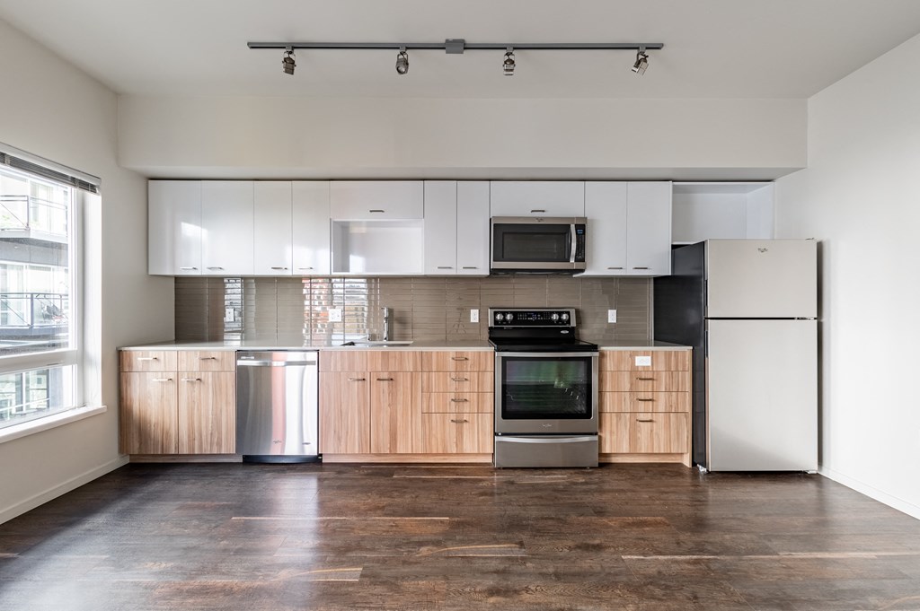 an empty kitchen with white cabinets and stainless steel appliances