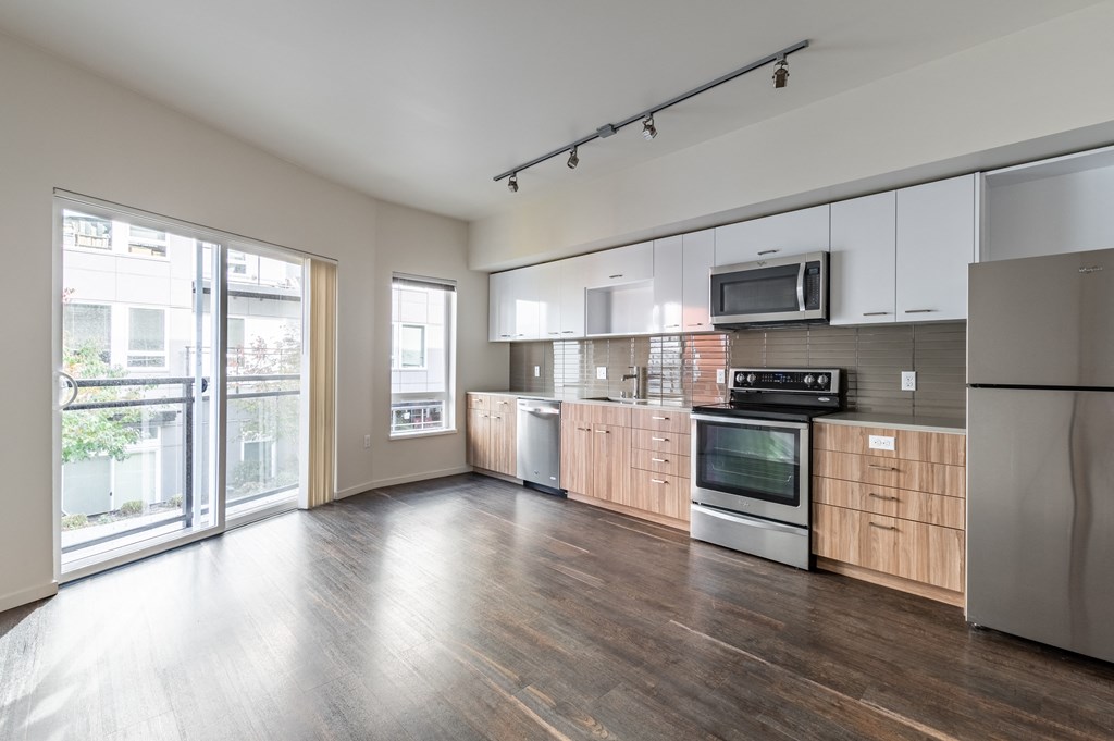 an empty kitchen with wood flooring and a sliding glass door