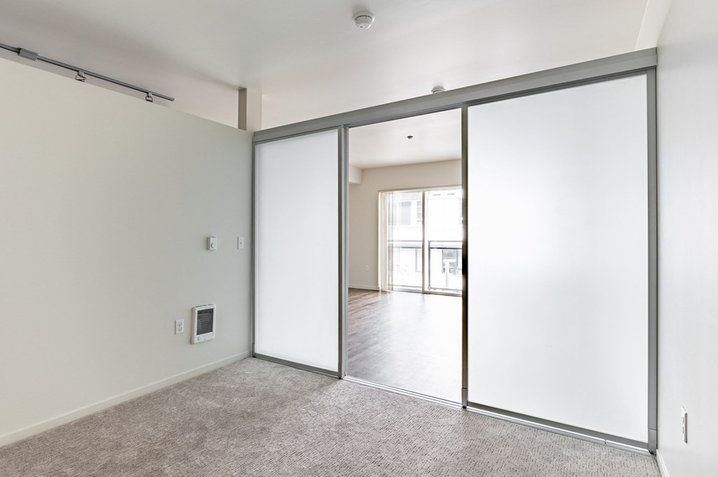 an empty living room with white walls and a sliding glass door