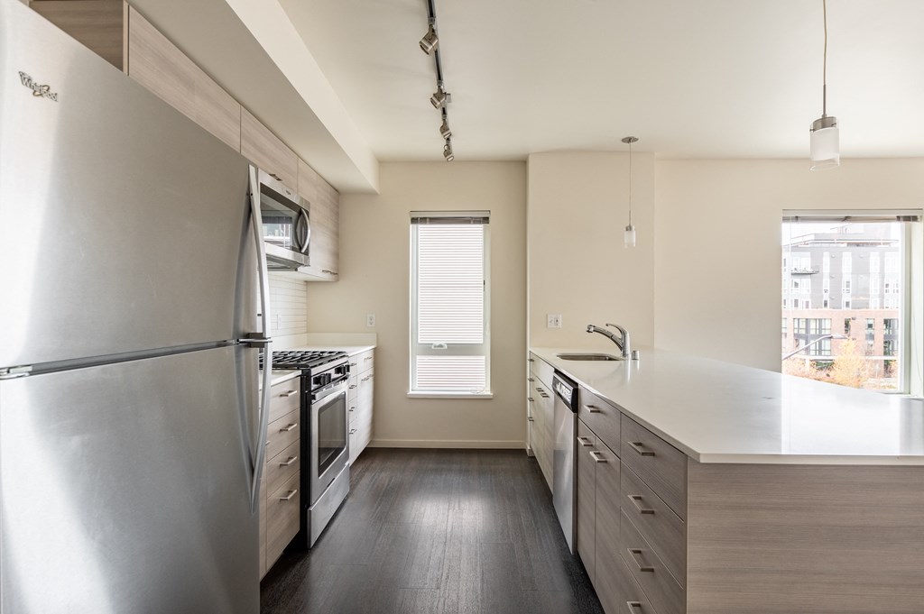 an empty kitchen with stainless steel appliances and white counter tops