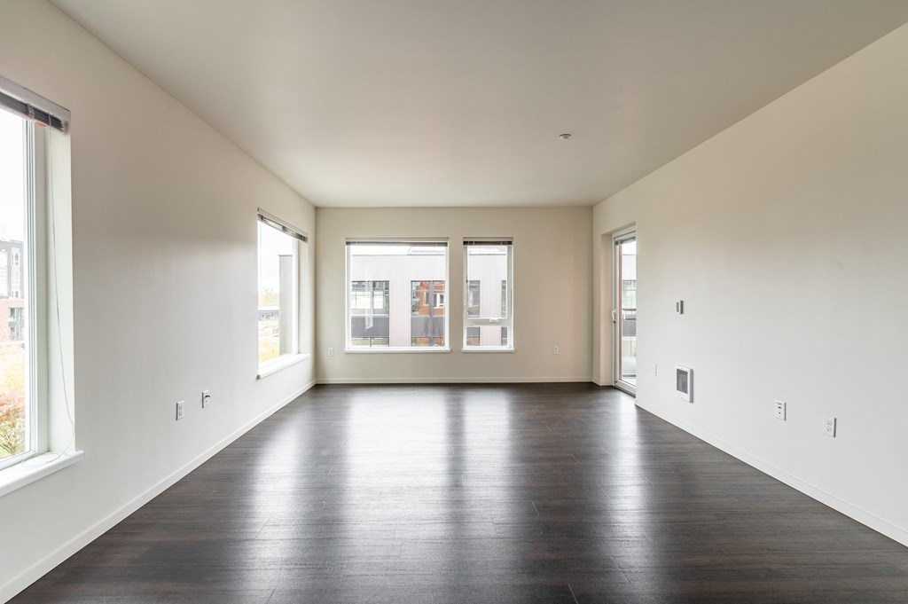 an empty living room with wood floors and white walls