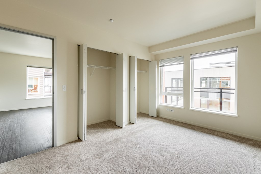 an empty living room with three windows and a door to a closet