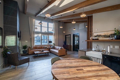 A modern open plan living and kitchen area with a wooden table in the middle.