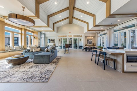 A spacious living room with a large sofa and a kitchen area with a bar stool.