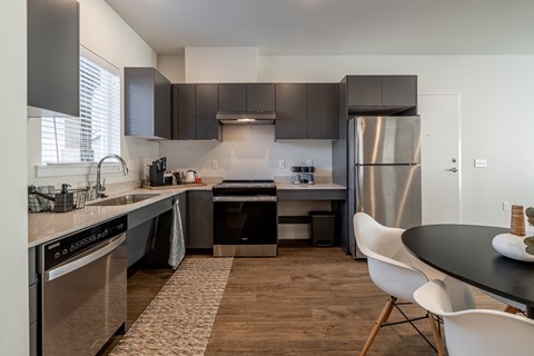 A modern kitchen with a black countertop and stainless steel appliances.