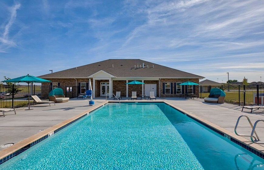 A swimming pool in front of a building with a black fence around it.