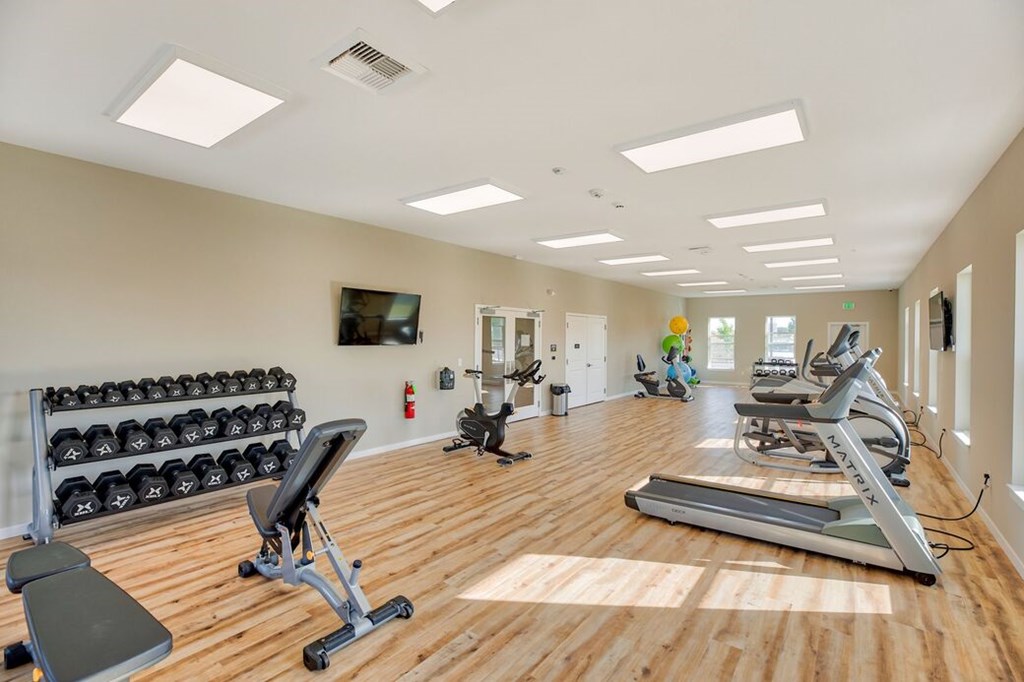 A well-lit gym with a variety of equipment including treadmills, weights, and exercise machines.