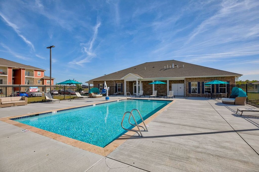 A large swimming pool in front of a building with a blue sky above.