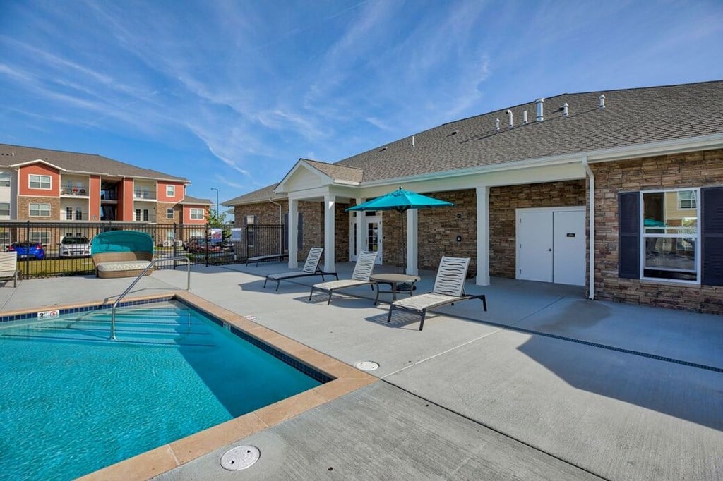 A pool area with a building and chairs.