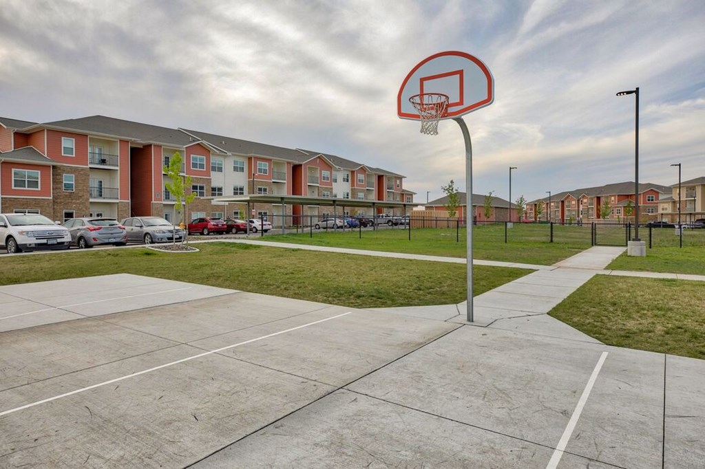 A basketball court with a hoop in the middle of a parking lot.