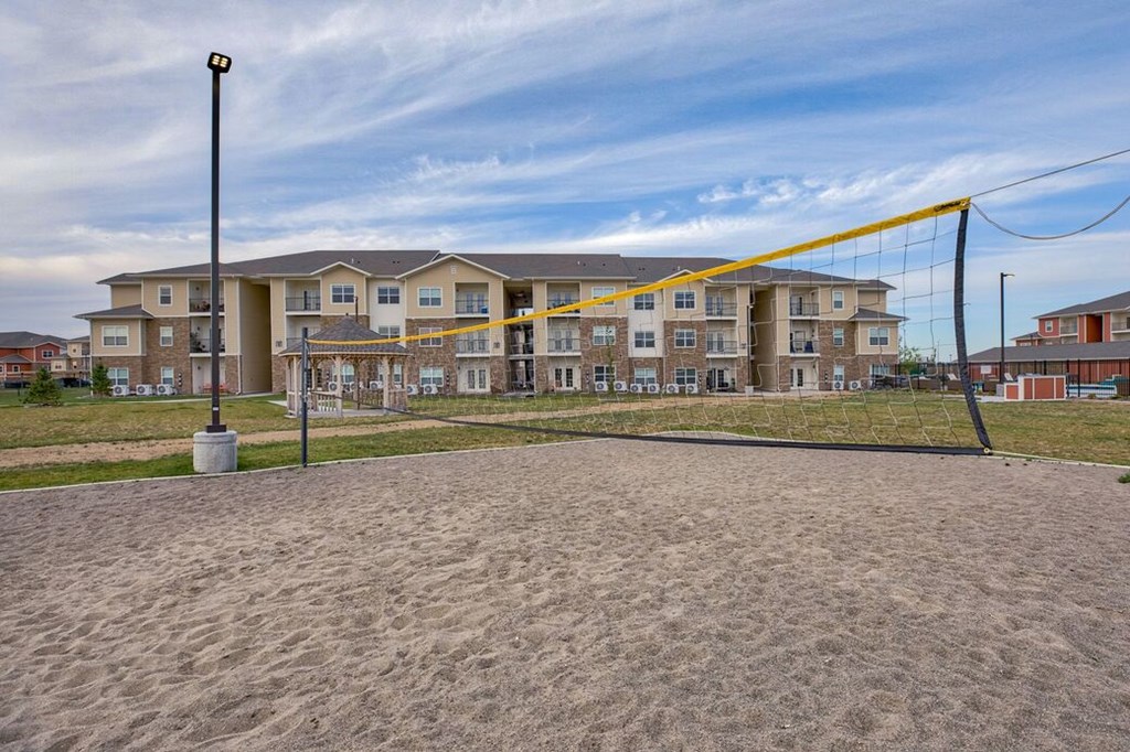 A sand volleyball court in front of apartment buildings.