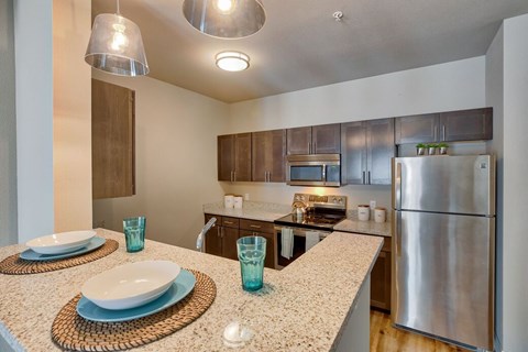 A kitchen with a stainless steel refrigerator and a countertop with a white plate and blue glasses on it.