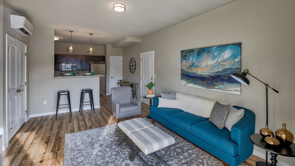 A living room with a blue couch and a painting on the wall.