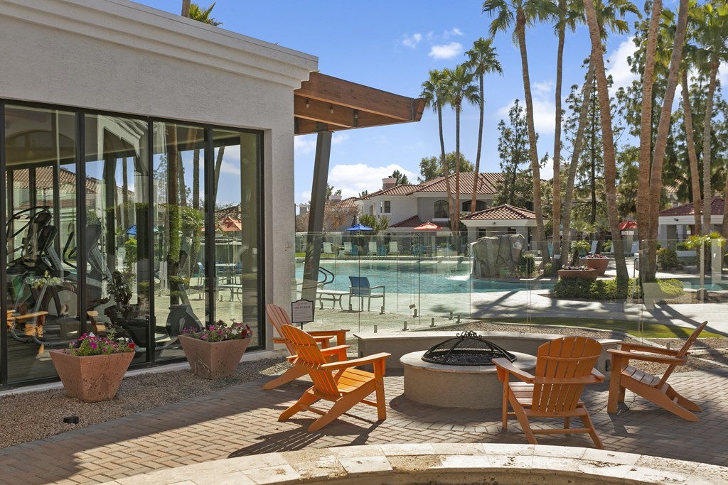 a patio with orange chairs near a swimming pool