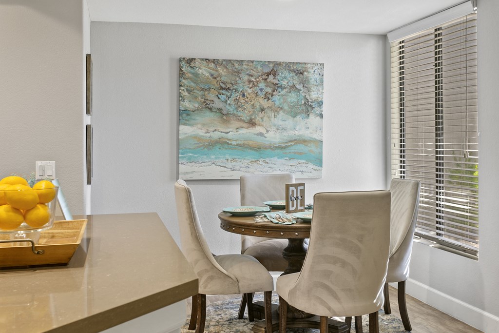 a dining room with a table and chairs and a painting on the wall