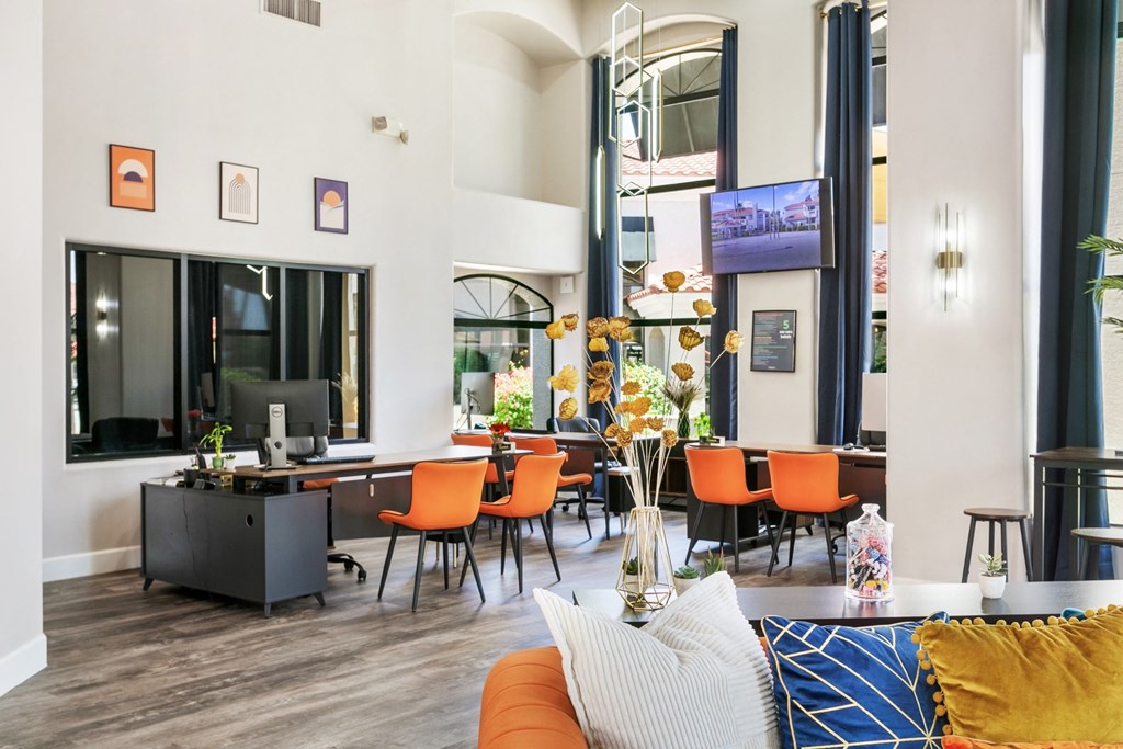 San Melia Apartments leasing office desks with orange chairs and a table