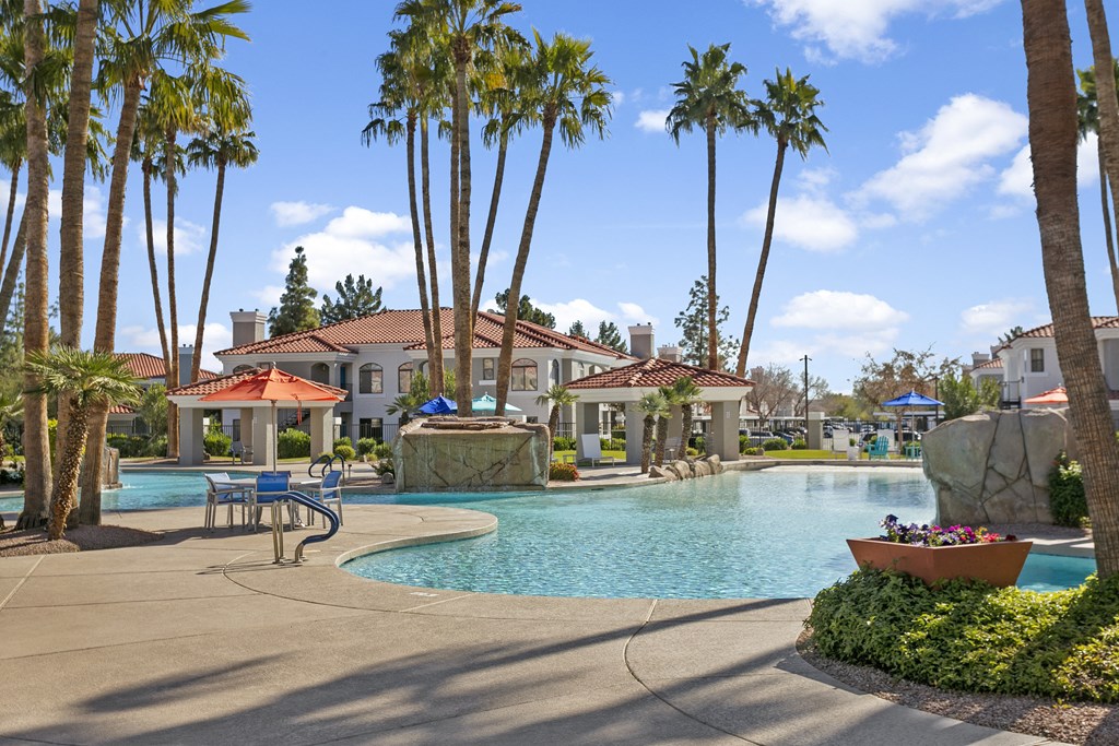 a swimming pool with palm trees and buildings in the background