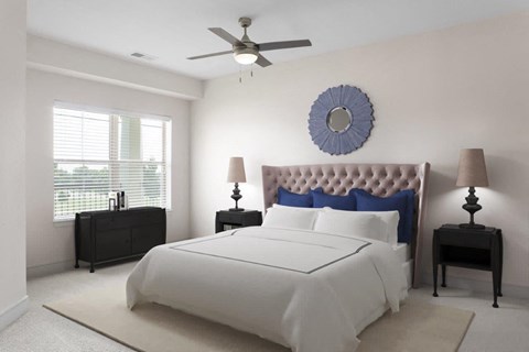 A bedroom with a large bed, a ceiling fan, and two lamps.