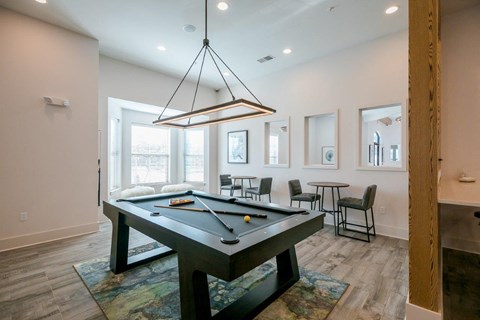 A pool table is in the middle of a room with a light hanging from the ceiling.