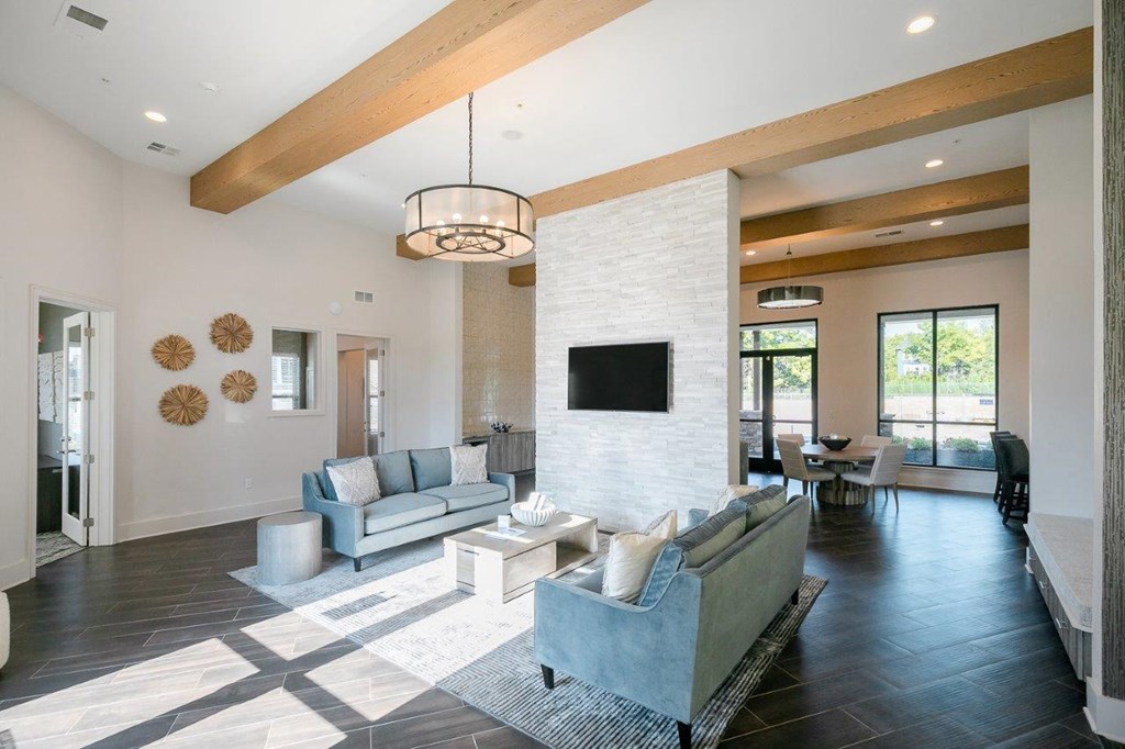 A modern living room with a grey couch and a white brick wall.