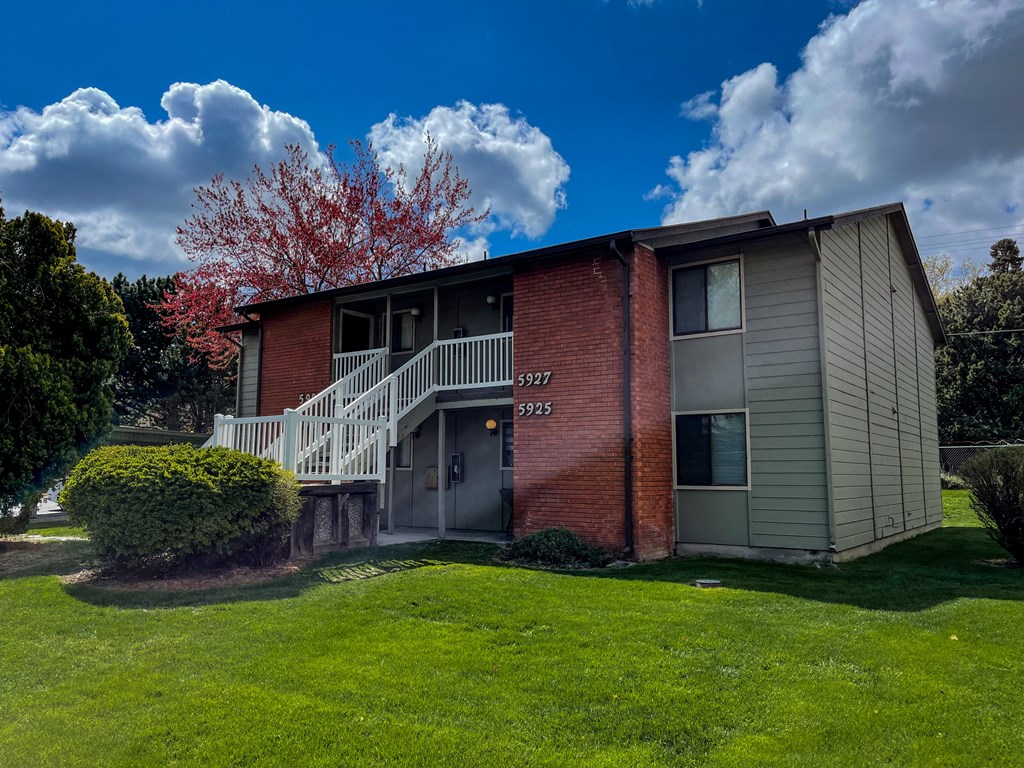 a red brick apartment building with a porch and a staircase