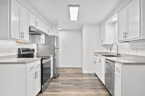 A modern kitchen with white cabinets and stainless steel appliances.