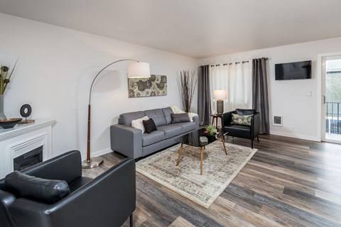 A living room with a grey couch, a black chair, and a fireplace.