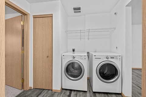Two washing machines in a laundry room with a door to the left.