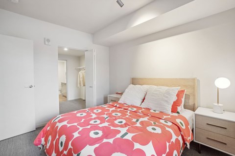 A bedroom with a bed, nightstand, and lamp.