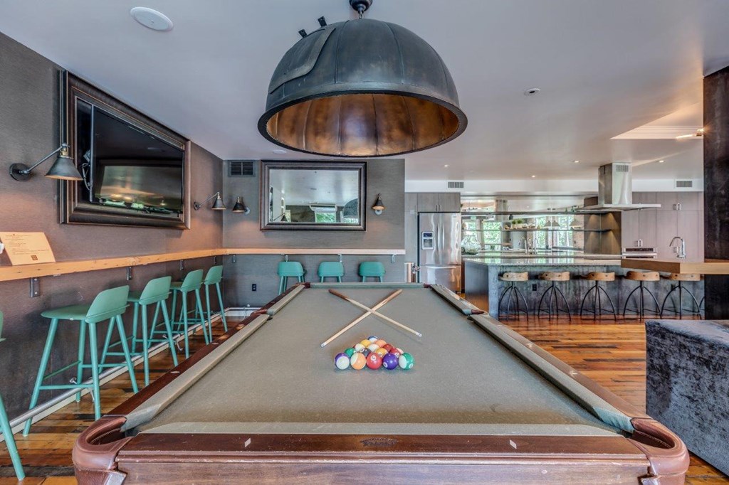 a pool table in a room with a bar and a tv